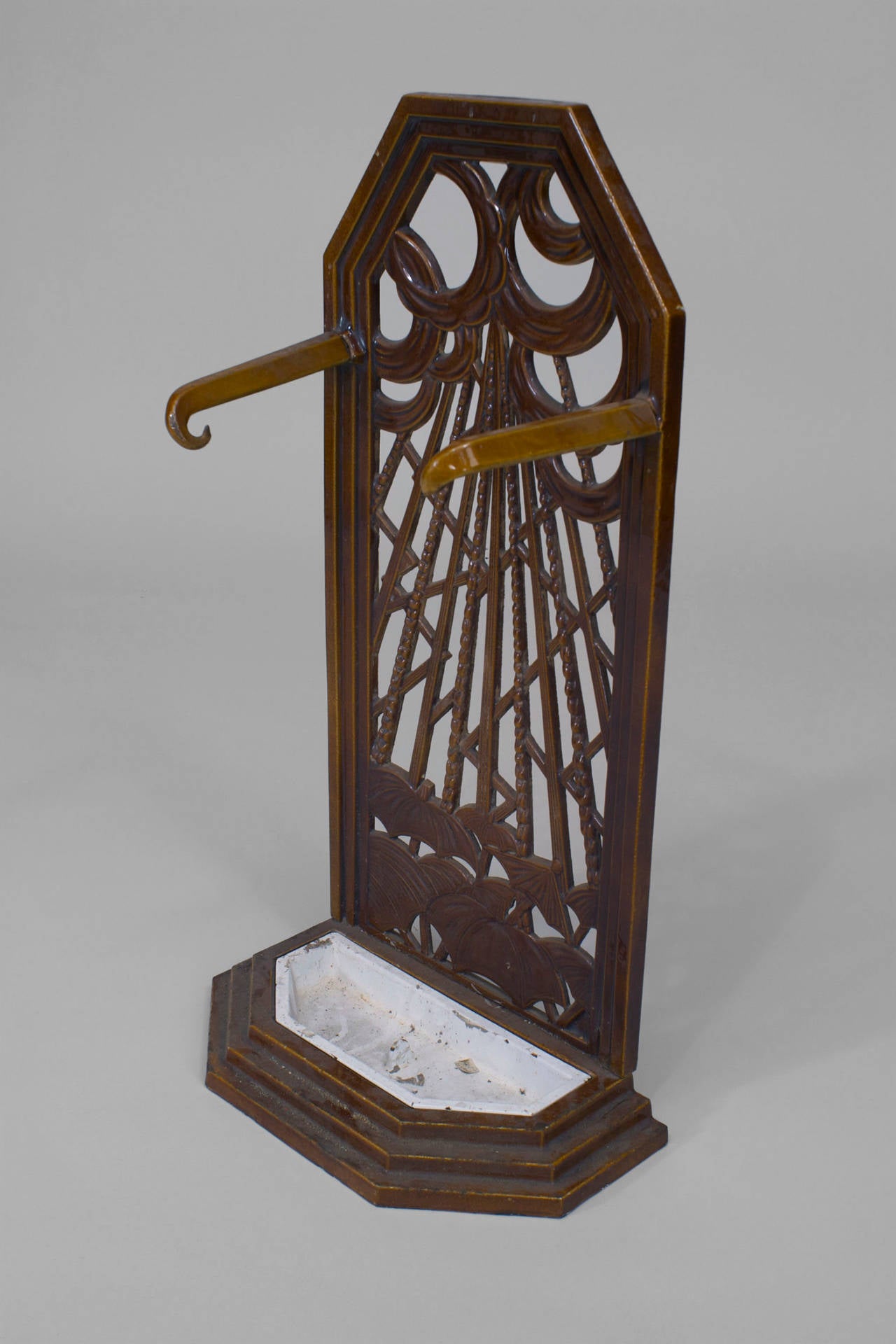 French Art Deco brown porcelain umbrella stand with filigree back design of clouds, rain, and umbrellas with 2 side hooks and a loose white bottom tray.
 