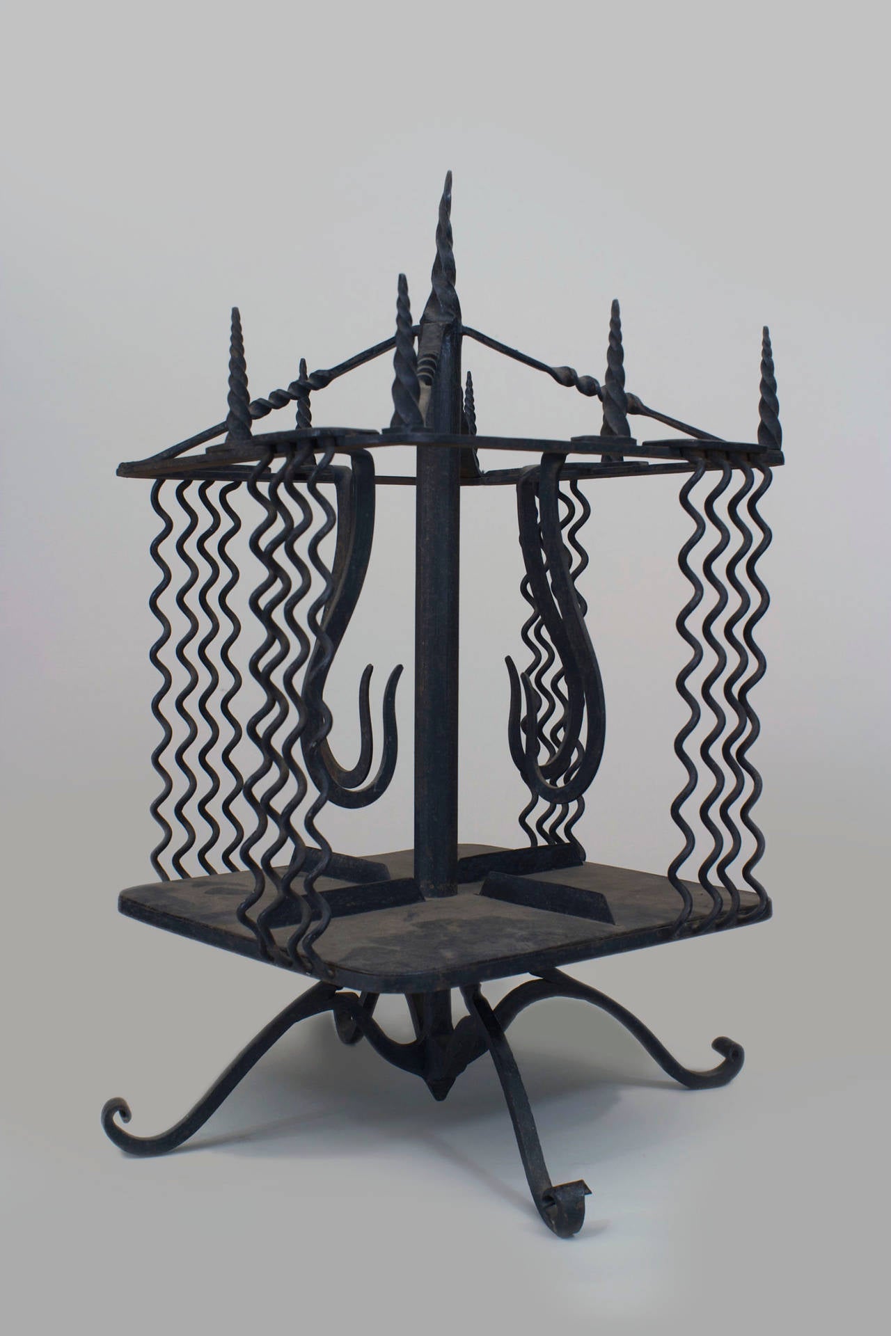 Italian Renaissance-style (19th/20th Century) wrought iron revolving table top book stand with finials on top and wavy design sides on a base with 4 scroll feet
