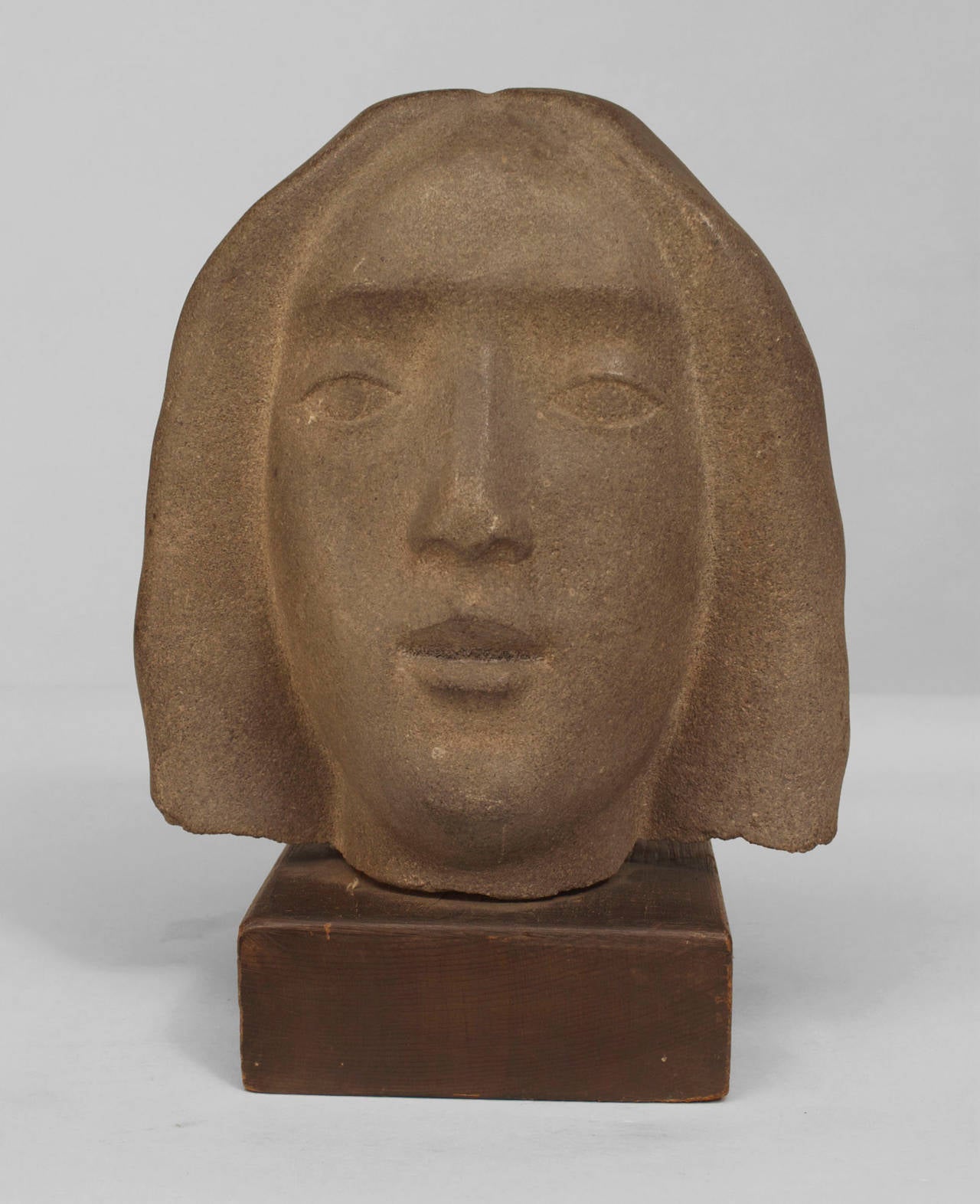 American Art Deco sculpture of a woman's head carved out of grey stone and
resting on a square wood base.