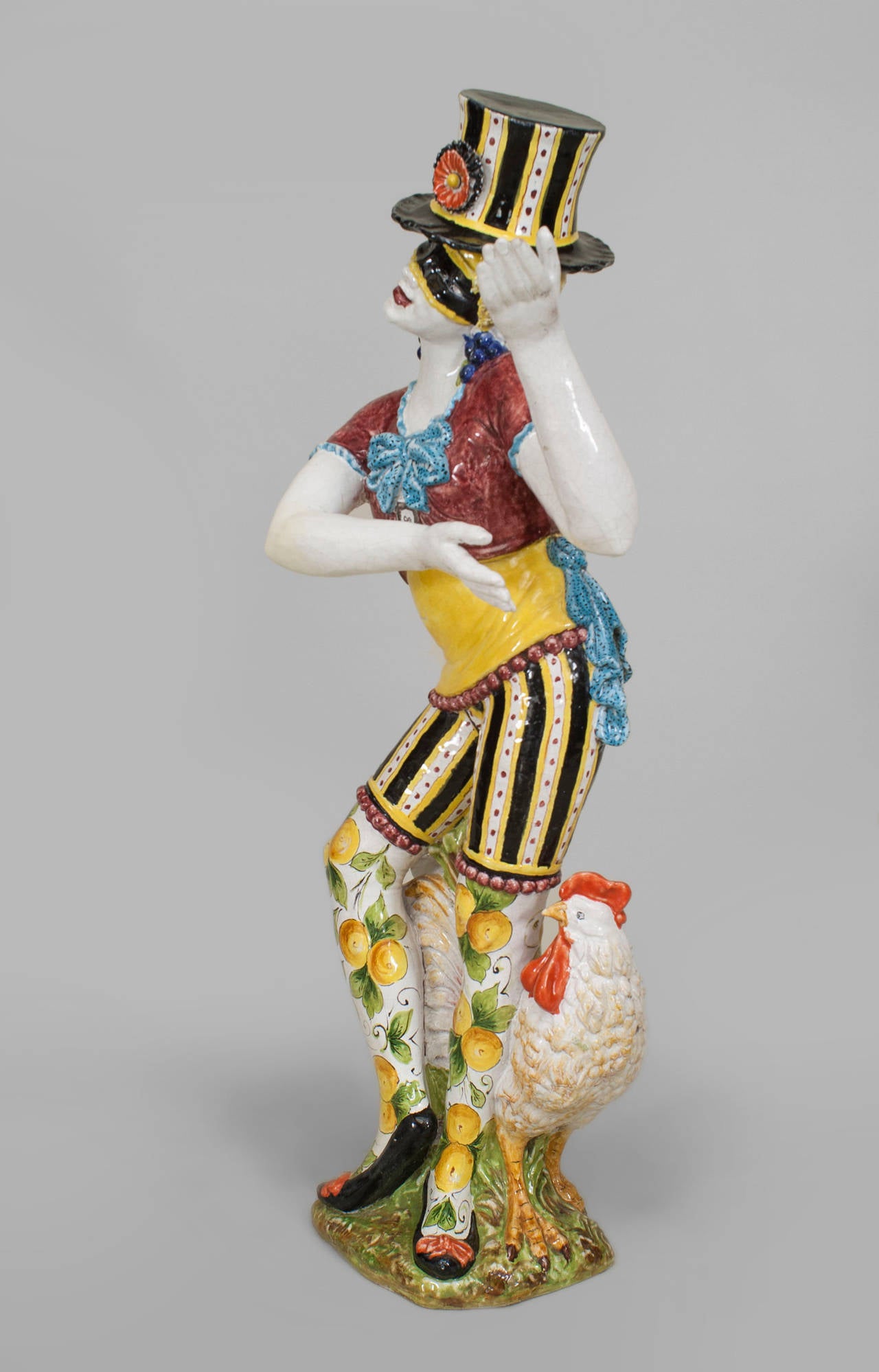 Pair of turn of the century Italian Majolica porcelain male and female
harlequin figures each wearing a top hat, striped pants and a red shirt.