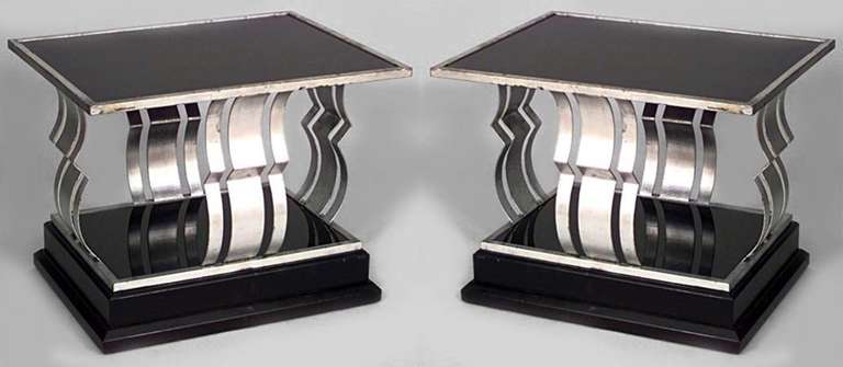 Pair of French Art Deco rectangular silver and black painted iron end tables with a black glass top and shelf framing open geometric design sides of silver and black painted iron.