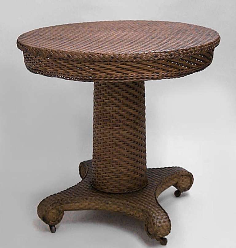 Nineteenth century American natural wicker end table bearing a Heywood Wakefield label. The table features a round woven top and column pedestal base resting upon a platform with four scroll feet.
