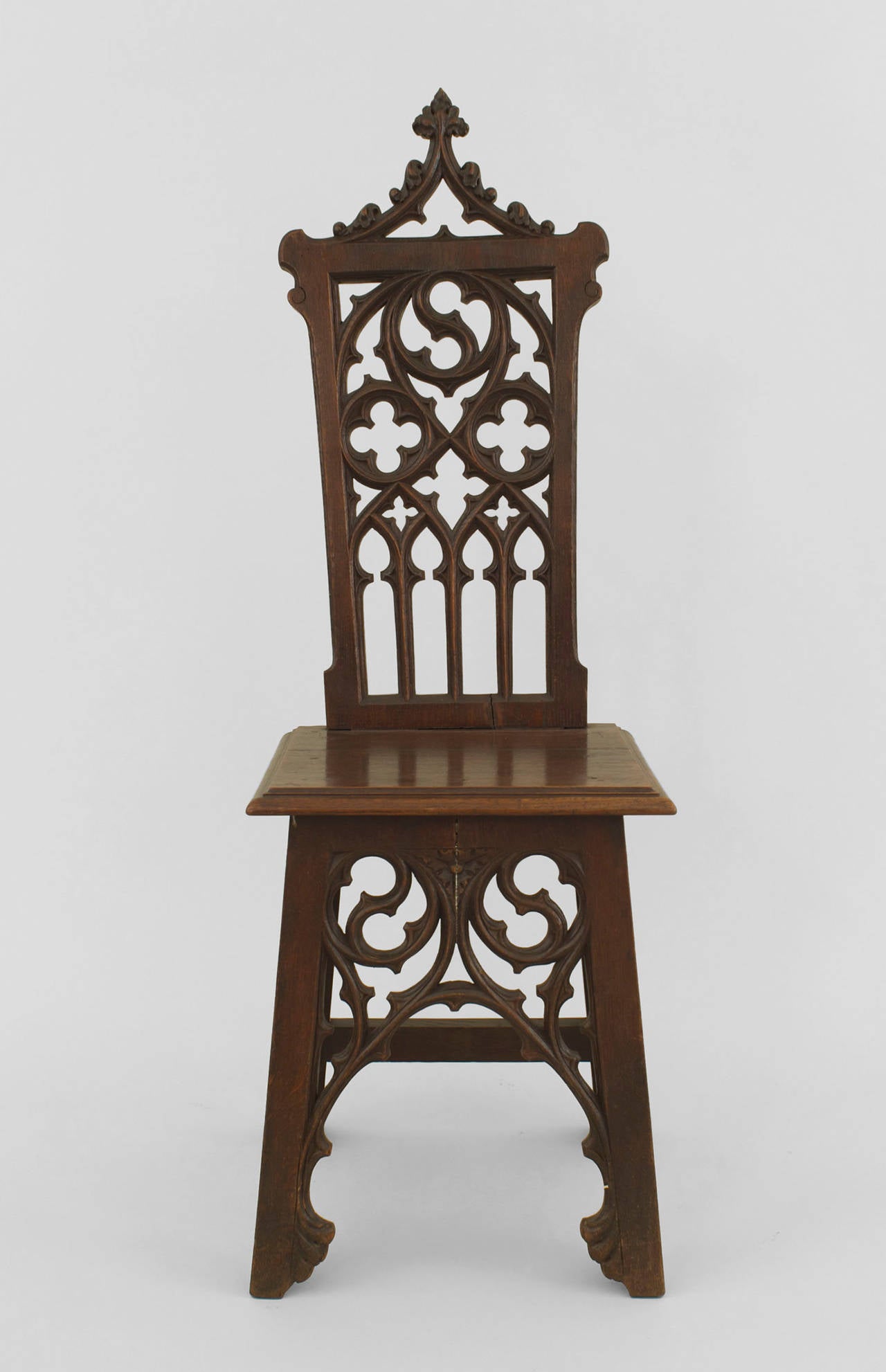 Pair of turn of the century English Gothic style oak side chairs with filigree pierced carved backs and wooden seats.
