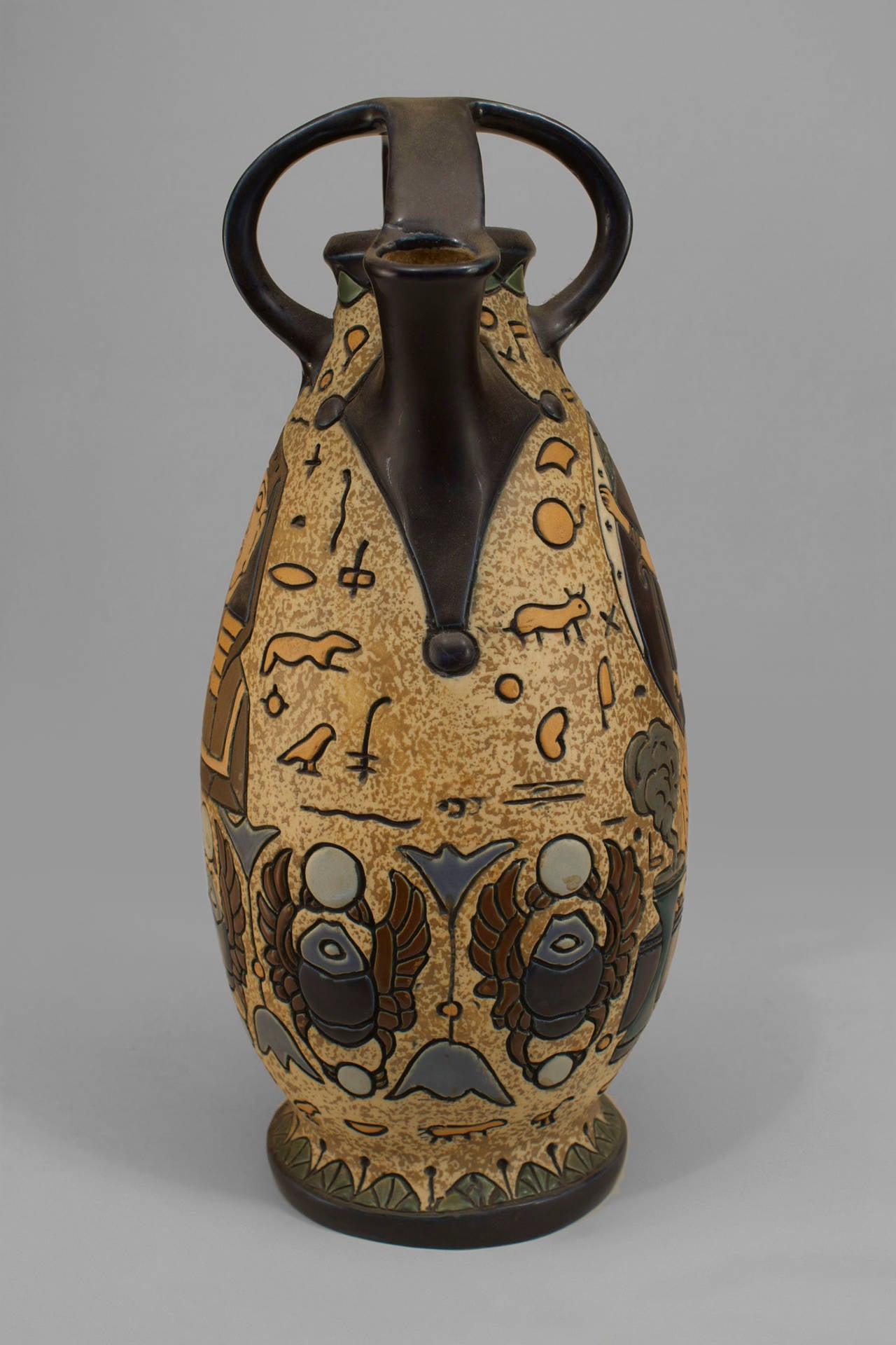 Middle Eastern Egyptian style (1st qtr 20th Cent-probably Czech) amphora vase with figures & motifs trimmed in black with a spout and open cage top.
