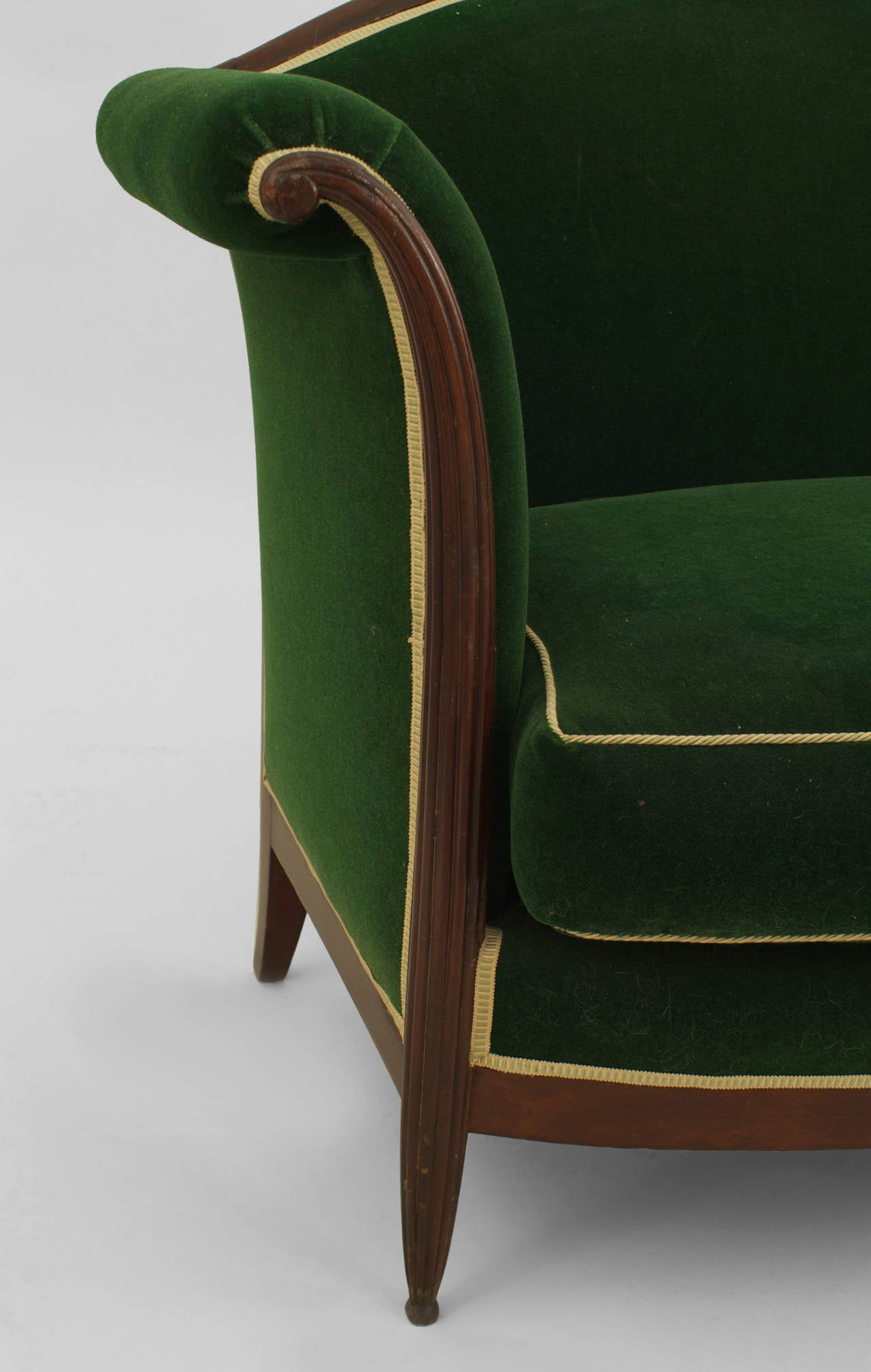 French Art Deco mahogany camel back loveseat with flaired form arms and fluted legs upholstered in green velvet with a seat cushion.

