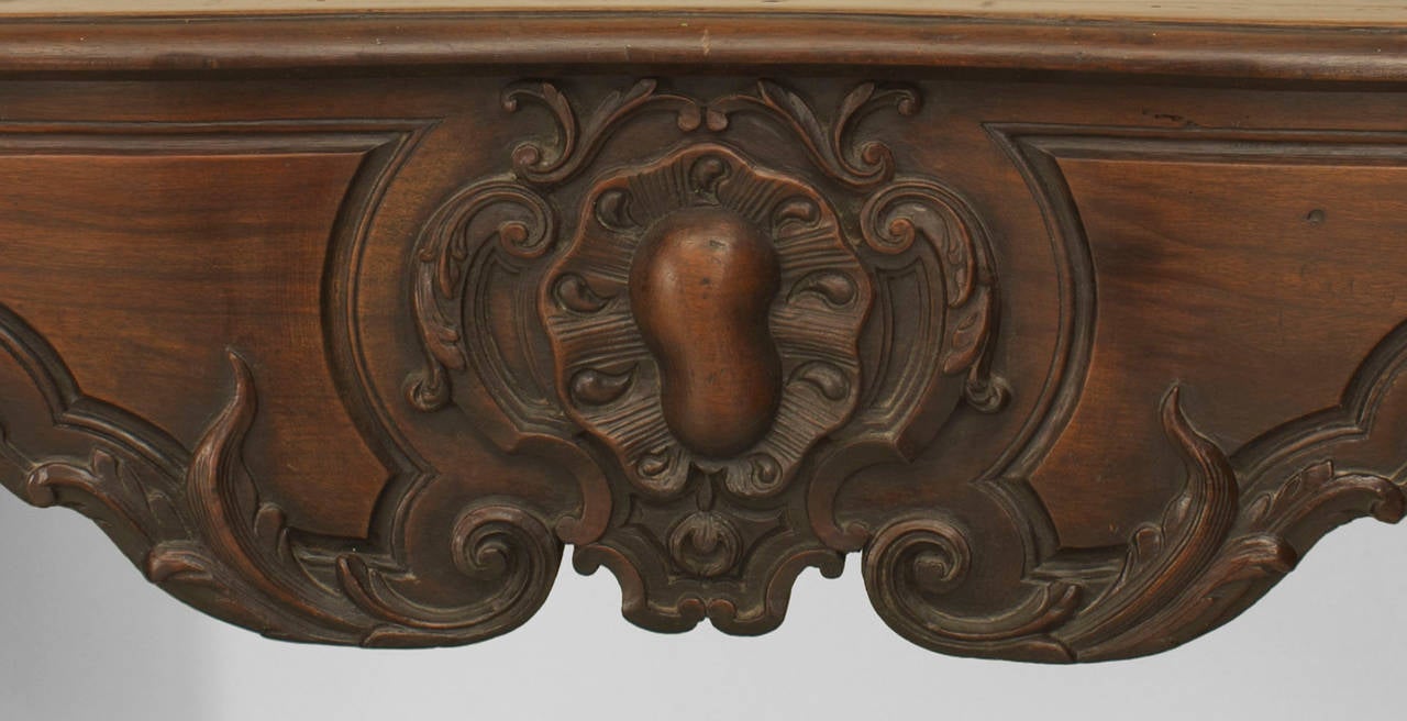 20th century, French provincial walnut fireplace mantel with shaped top and center carving with scroll sides.