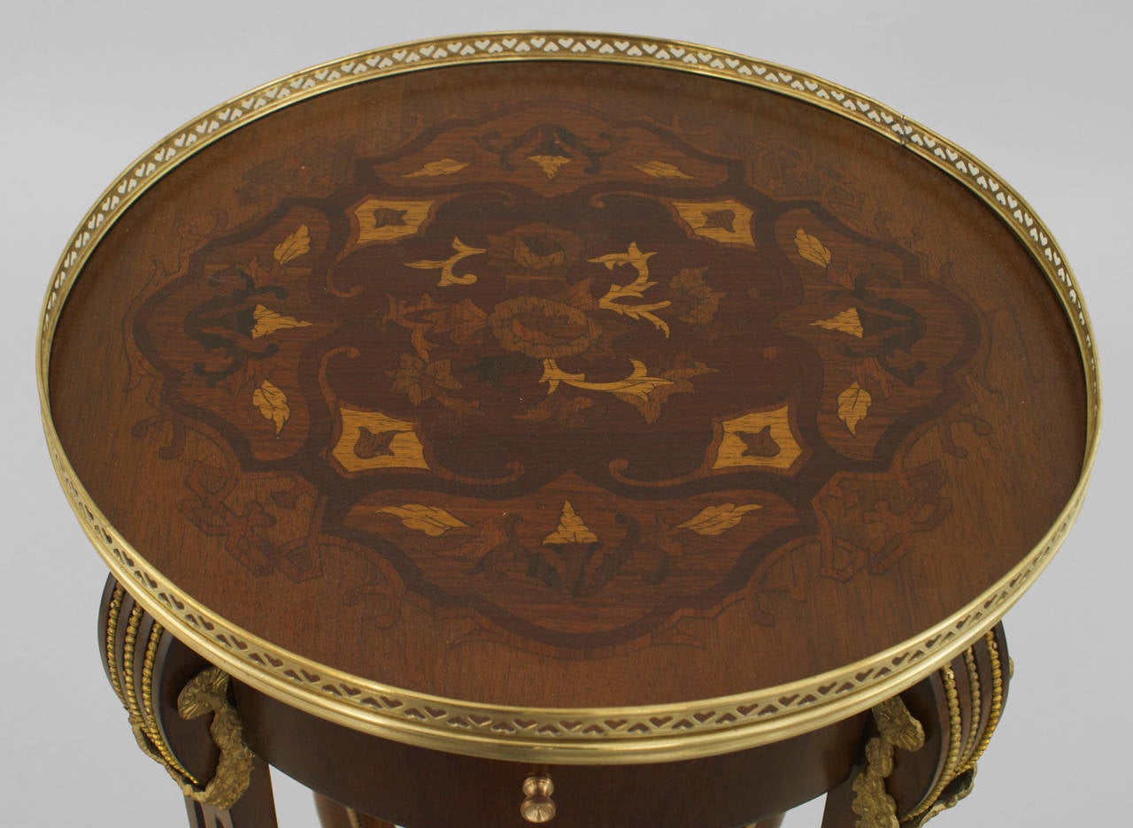 Pair of French Louis XVI-style (19/20th Century) round end tables with a floral inlaid top having brass filigree gallery and a shelf with a bronze basket and trim. (PRICED AS Pair)
