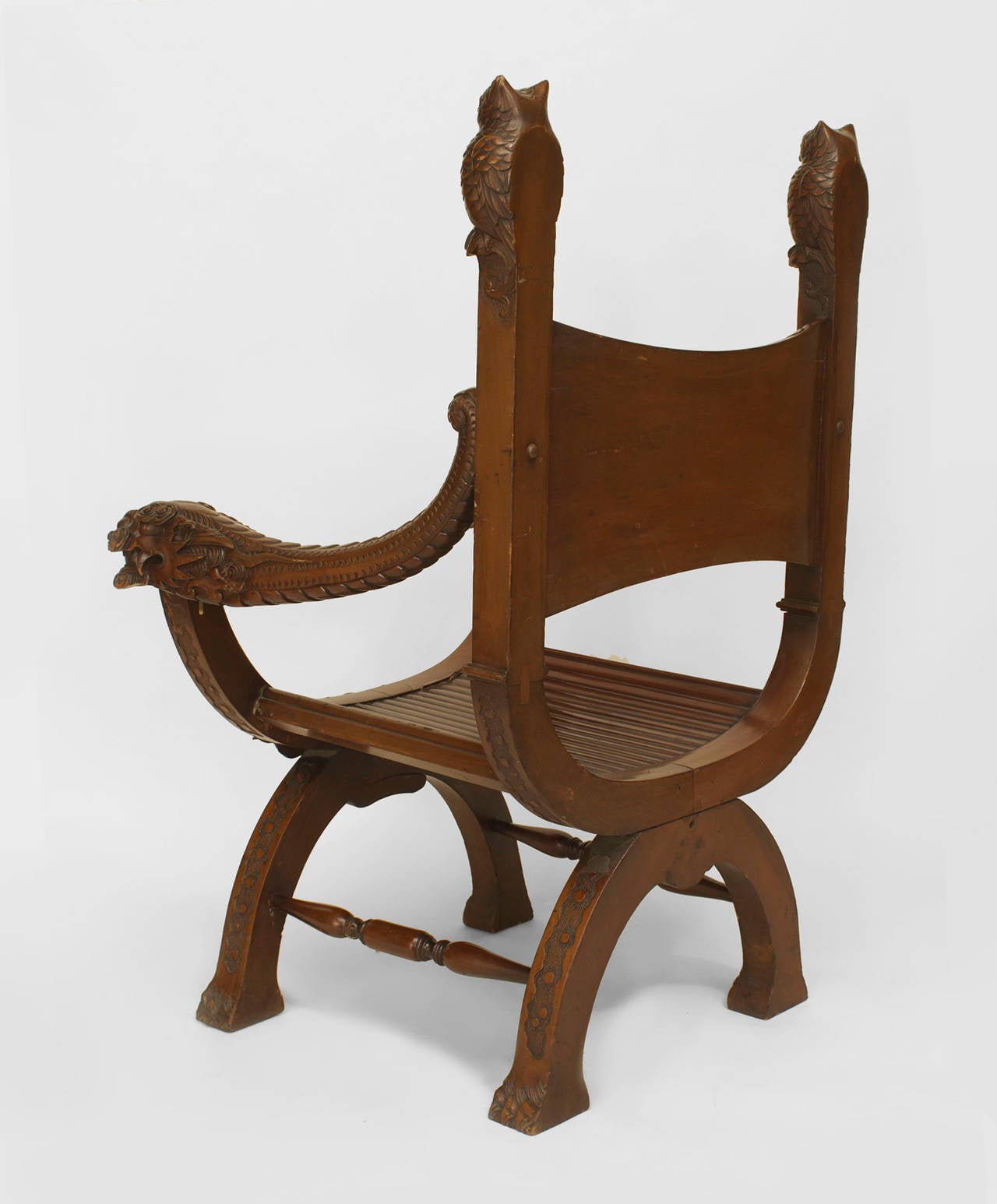 Asian Japanese (Early 20th Century) mahogany arm chair with a slat design saddle form seat and a carved back panel with owl finials and dragon arms.
