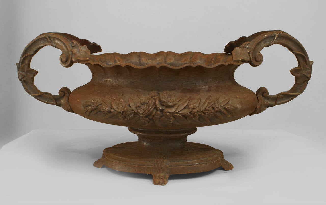 Pair of 19th century French oval shaped iron planters with scroll design sides and a floral relief design and scalloped top.