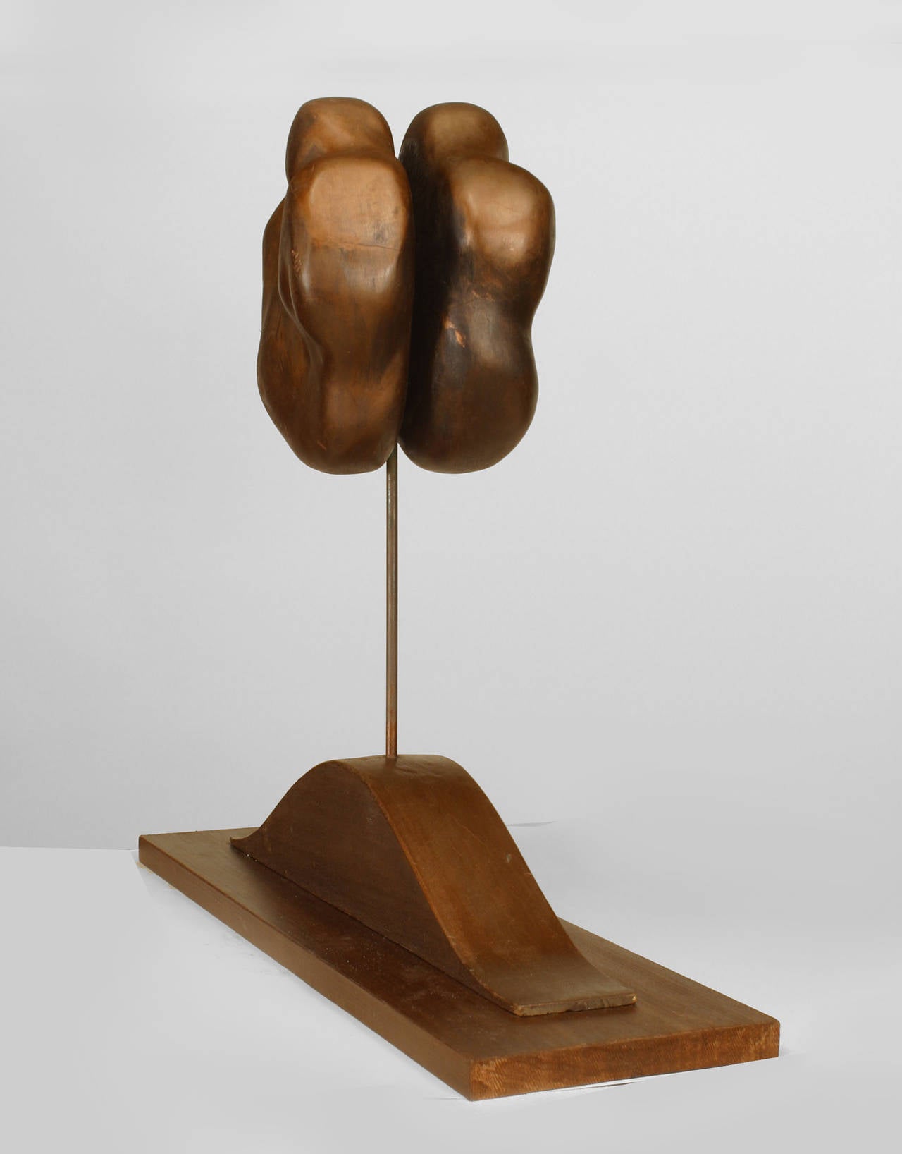 20th century American abstract wood sculpture of two parallel freeform spheres raised on a narrow base.
