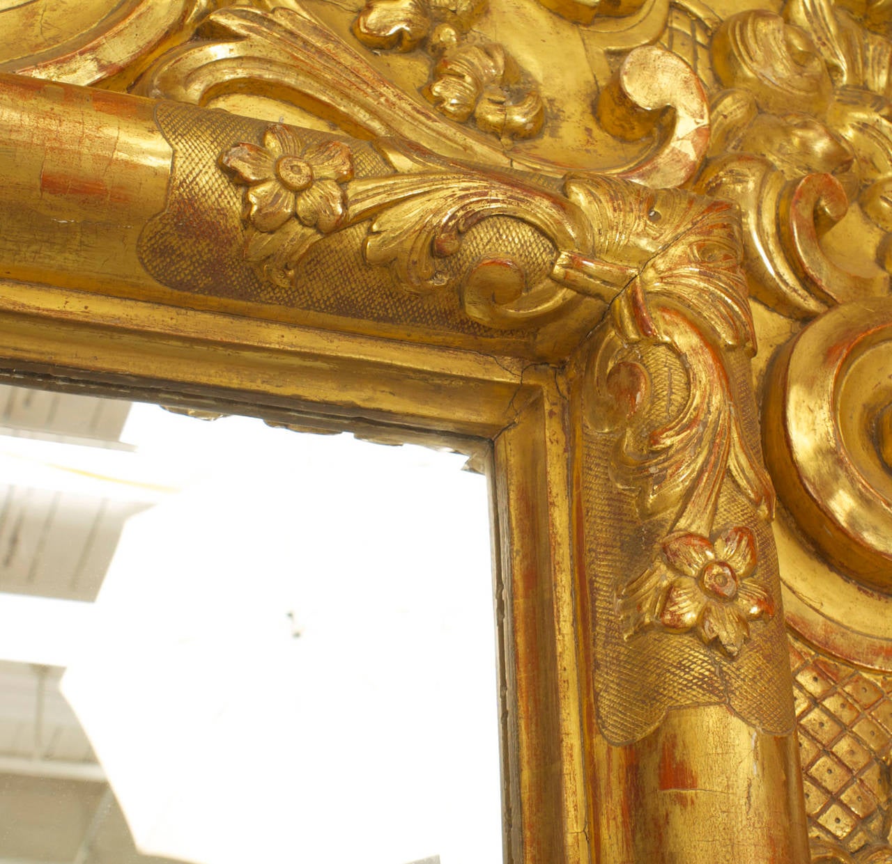 Italian Rococo (18th century) large, ornately carved giltwood wall mirror with a floral and scroll design frame with a pediment top featuring two cupid heads.
     