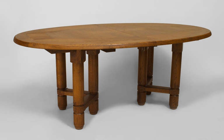 1950's French dining table by Guillerme et Chambron. The table is composed of oak and features an oval, geometric design top over a pair of pedestal bases, each with three legs joined by a stretcher. Each of the table's leaves measures 20 inches.