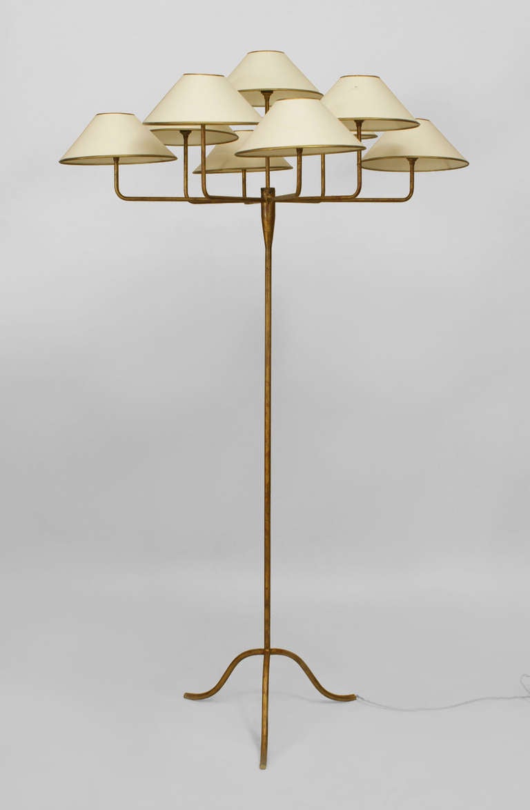 1950's French gilt metal floor lamp by Jean Royere. This lamp features a minimalistic long-stemmed, tripod base supporting a canopy of nine L-form arms with gold-trimmed conical shades.