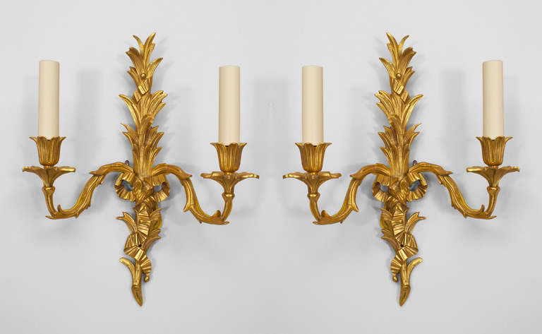 Pair of twentieth century French Louis XV style gilt bronze wall sconces, each with palm design forms and bow knot centers issuing forth two arms with floral cups.

Additional pair available, priced per pair.