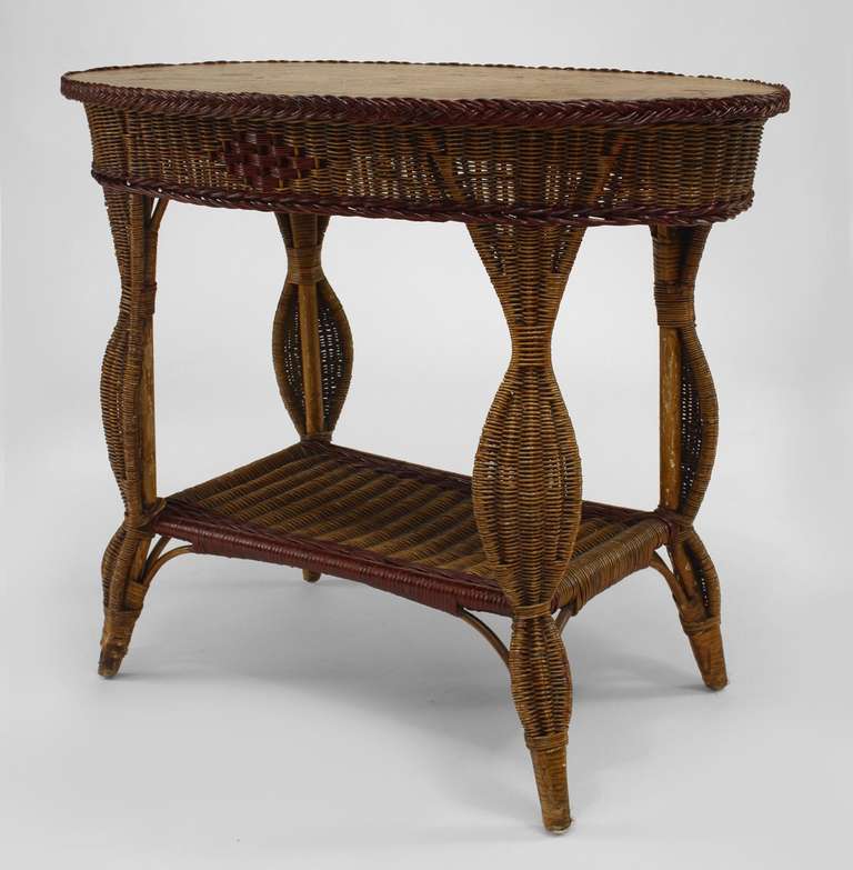American Art Deco end table composed of red trimmed natural wicker with an oval painted wood top above four shaped legs and a shelf stretcher.