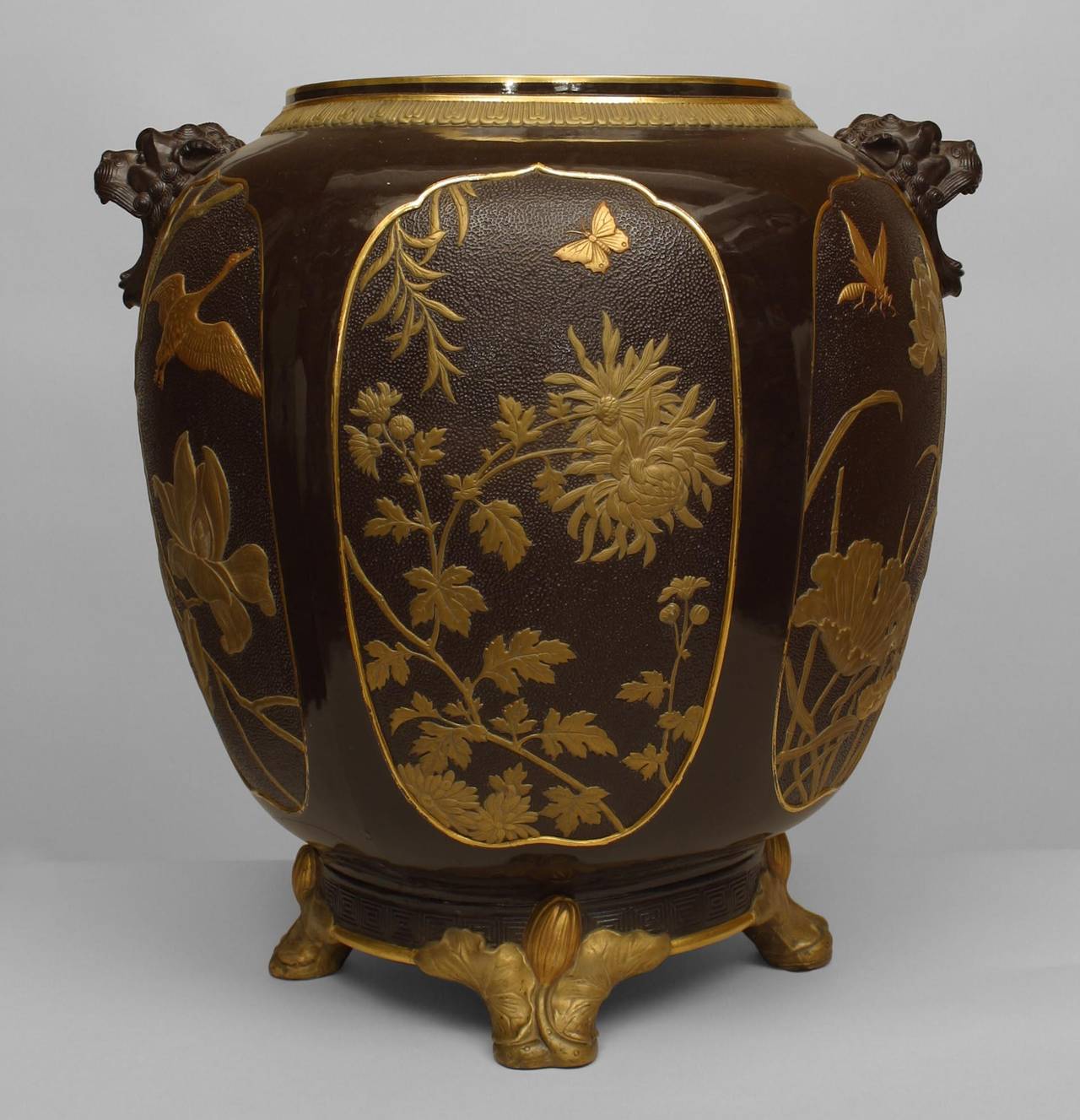 19th century English Regency style brown porcelain jardiniere with Chinoiserie
design and gold trim with lion head sides standing on 4 feet (impressed Minton with numbers). (as is- hairline crack to base)