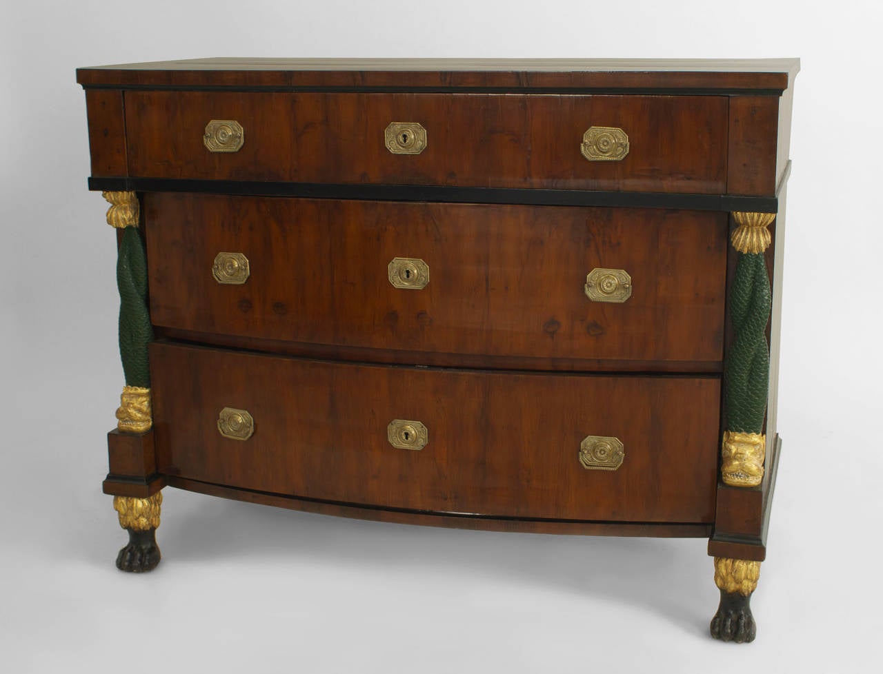 Pair of early-mid 19th century Continental Baltic mahogany bow front three-drawer
chests with ebonized trim and carved gilt and green painted dolphin sides with claw feet.