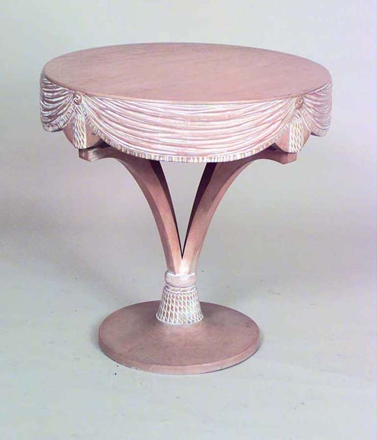 American Art Moderne bleached maple end table with circular top above a swag and tassel carved apron and scrolling uprights. (Attributed to GROSFELD HOUSE)
