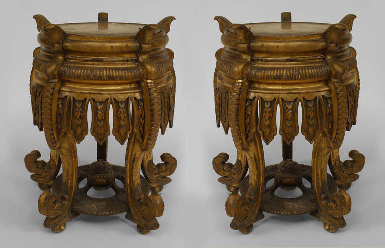 Pair of nineteenth century Chinese round gilt carved taborets with elaborate aprons carved in imitation of hanging ribbons. Each table rests upon five inwardly curved legs joined by a circular stretcher topped with a carved animal surrounded.