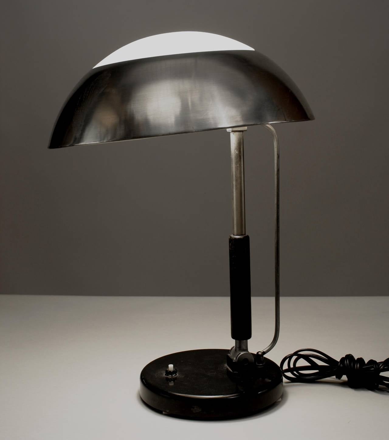 Lámpara de sobremesa Art Decó Bauhaus alemana con pantalla de aluminio cepillado y cristal blanco sobre columna y base de metal ebonizado regulable. (atribuida a KARL TRABERT).
