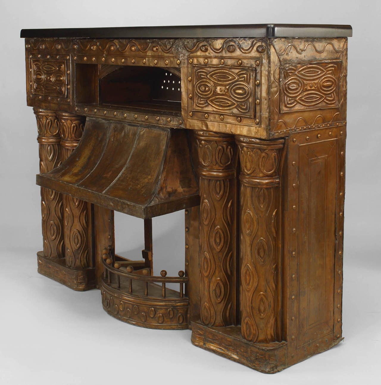 Austrian Secessionist embossed brass fireplace with double column design sides and hooded center below an open shelf with a (modern) ebonized top.
 
