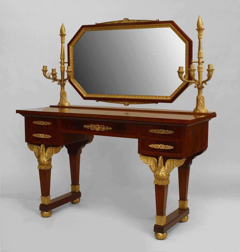 French Empire (19th Century) mahogany vanity / dressing table with gilt bronze trim and swan supports on legs with a rectangular form mirror attached by a Pair of 3 arm candelabra.
