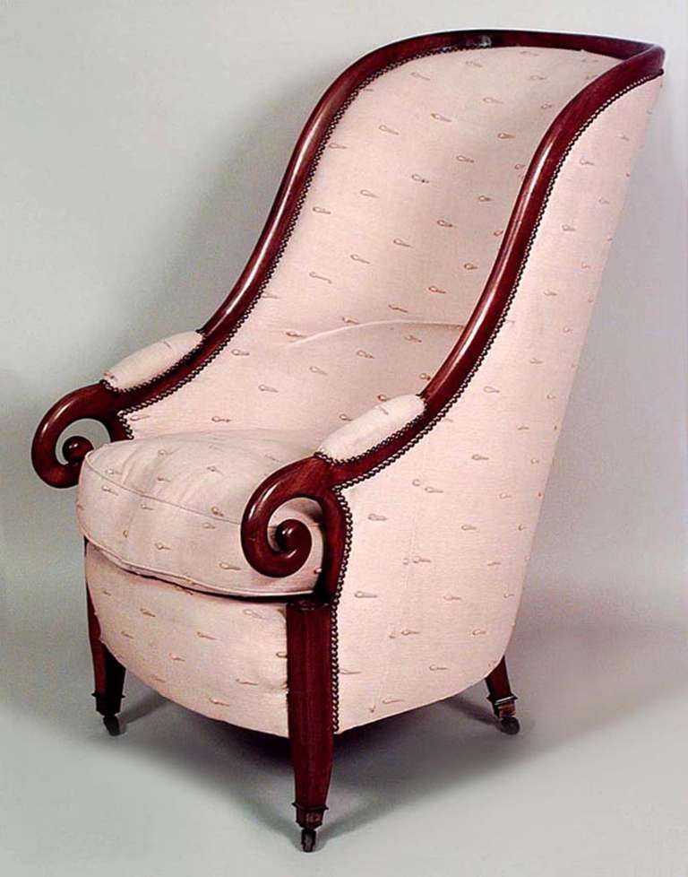 19th century English Regency style club chair with curlicue arms and a rounded high back with cream upholstery and a partially exposed walnut frame.
