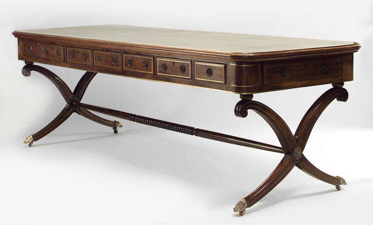 Early 19th century, English Regency brass inlaid mahogany library writing table or desk with a green leather inset top over frieze drawers on x legs joined by a turned stretcher. 