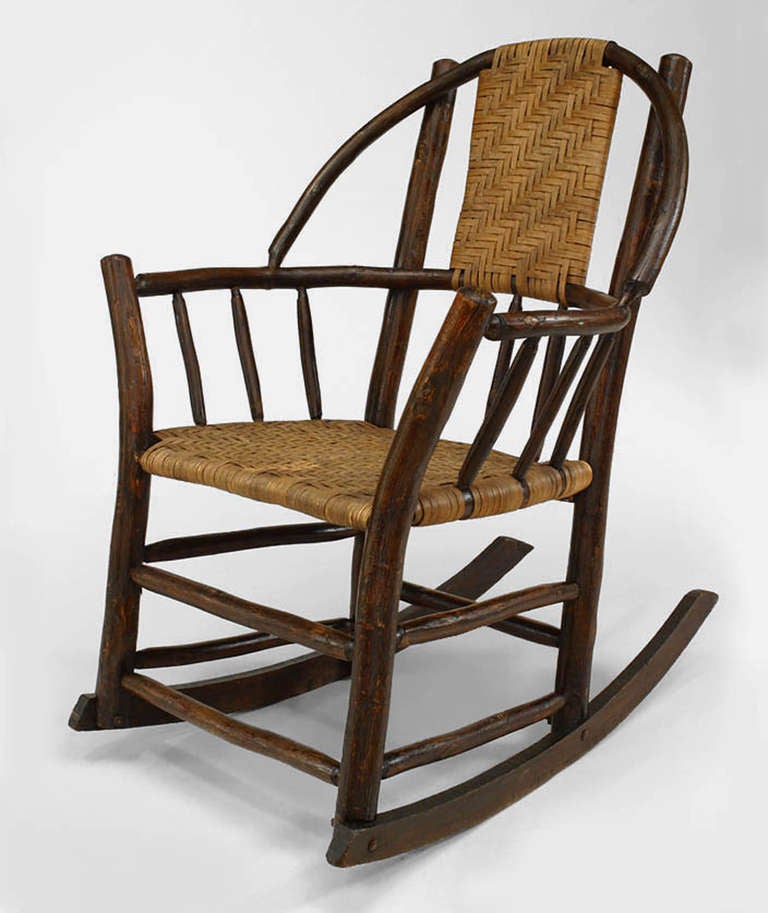 Attributed to the esteemed Old Hickory Furniture Company, this rocking armchair features a hoop back and a rattan splat back and seat. The piece is branded 
