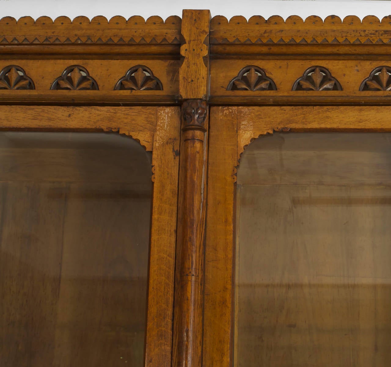 Turn of the century English Arts and Crafts yew wood bookcase with three glass doors over three solid doors with a carved and scalloped pediment top.