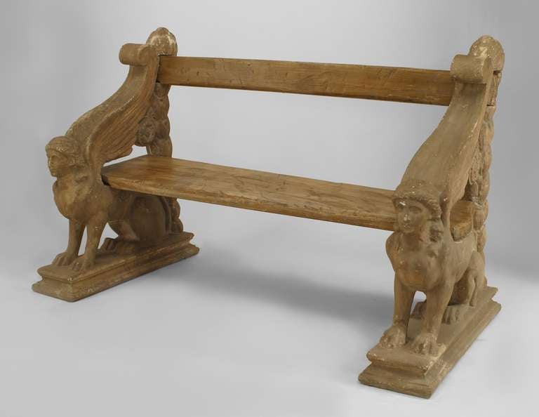 19th century English Regency stone garden bench featuring a slat wood seat and back and distinctively carved sphinx form sides.