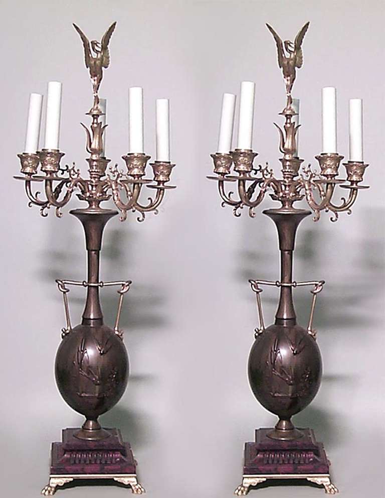 Pair of French Louis XVI style candelabra signed H. Cahieux and F. Barbedienne, 1880. Each vasiform, patinated bronze candelabrum is decorated with bird reliefs, a motif repeated at the bird-form finial seen rising above five curved ormolu arms. The