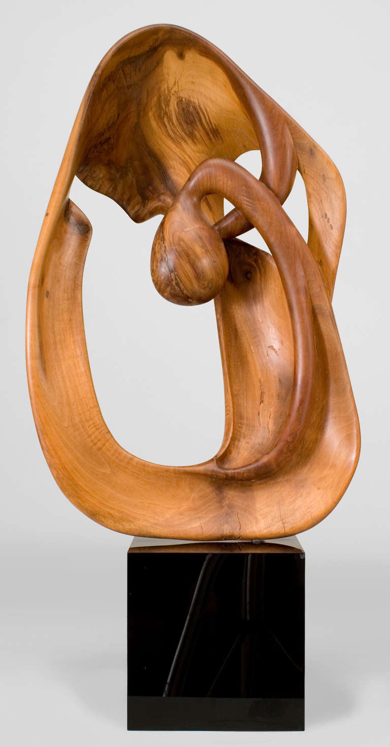 Signed by Tom Williams and dated 1977, this Post-War American abstract sculpture is composed of a smooth, curvilinear wooden form that rests atop a cubic black lacquer base.