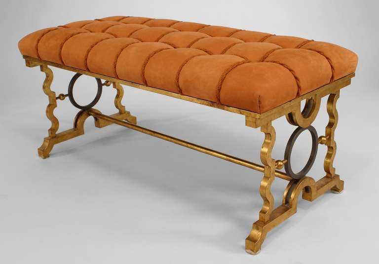 Pair of gold-painted iron and bronze benches in the manner of Gilbert Poillerat. Each bench features whimsical, open design, geometric stretchers and a tufted beige suede seat.