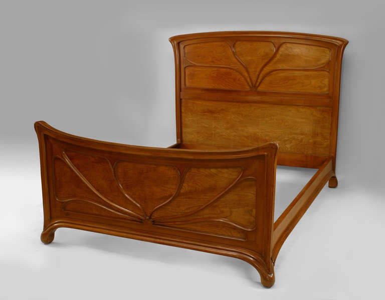 Signed by the French designer Landry, this queen sized bed is composed of rich maple wood and includes its original headboard, footboard, and rails, the carving of which conforms to the sensually curving, floral-inspired forms that epitomize the Art