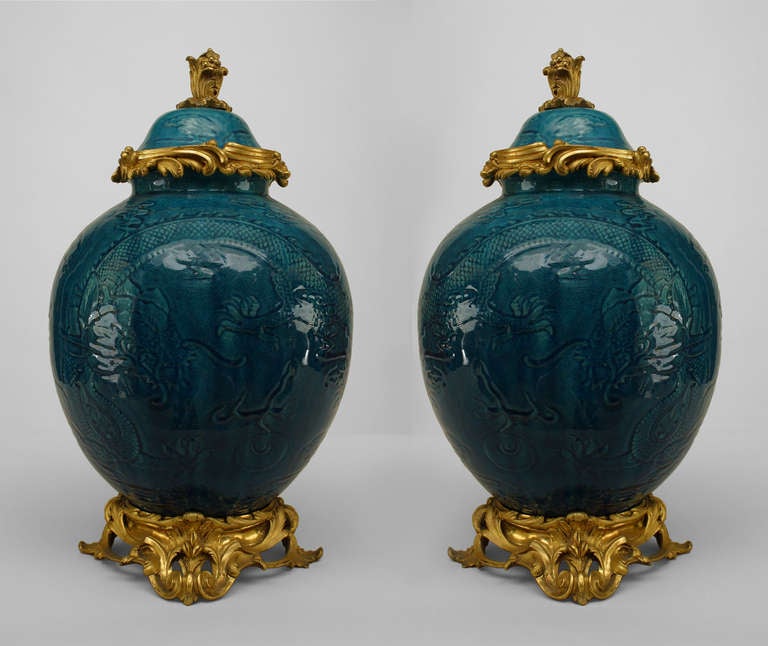 Pair of Chinese turquoise porcelain vases featuring striking bronze dore accents at their lids and bases as well as surfaces bearing traditional decorative elements such as five-toed dragons and flaming clouds in bas relief.