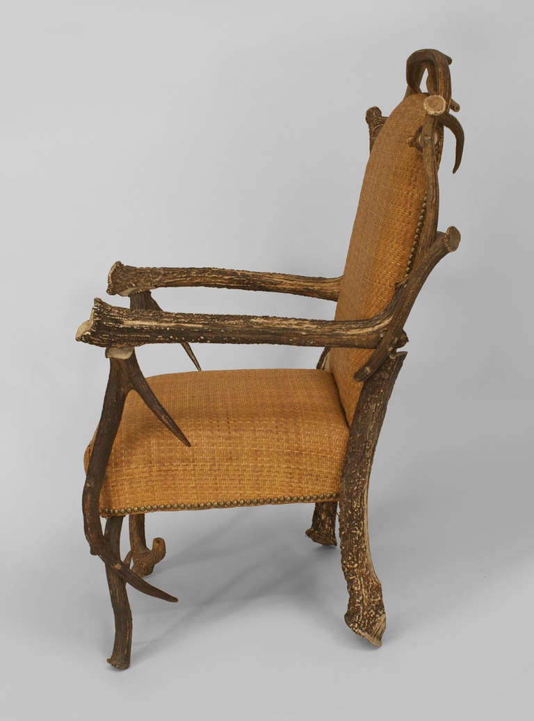 Large Continental rustic horn chair dating to the first half of the twentieth century. The seat and back are upholstered in light woven caning trimmed with brass nail heads and supported by a four-legged frame composed of stag antlers.
