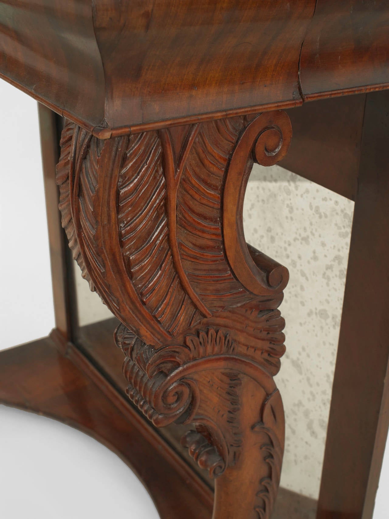 English Regency (circa 1820) mahogany narrow console table with acanthus carved legs ending in paw feet and a mirrored back.
