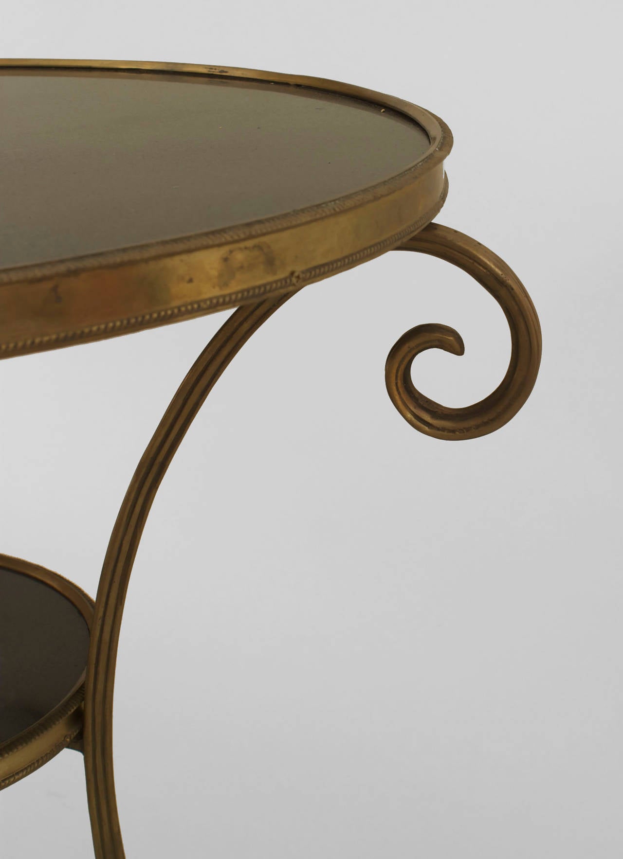 French Charles X-style (19/20th Century) round bronze gueridon end table with 3 scroll legs supporting a black marble top and shelf with a lower stretcher having a finial.
