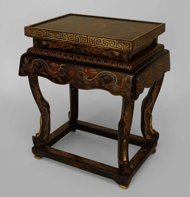Pair of Chinese black lacquered Palace tables featuring decorative painted designs, including traditional gold dragon motifs, and resting upon low cabriole legs connected with a rectangular stretcher. These pieces likely date to the nineteenth