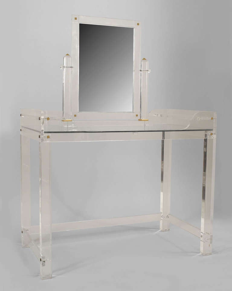 1940's American lucite and glass dressing table featuring a rectangular top, four narrow rectangular legs joined by a three-sided stretcher, and an adjustable vanity mirror resting atop the table's surface.