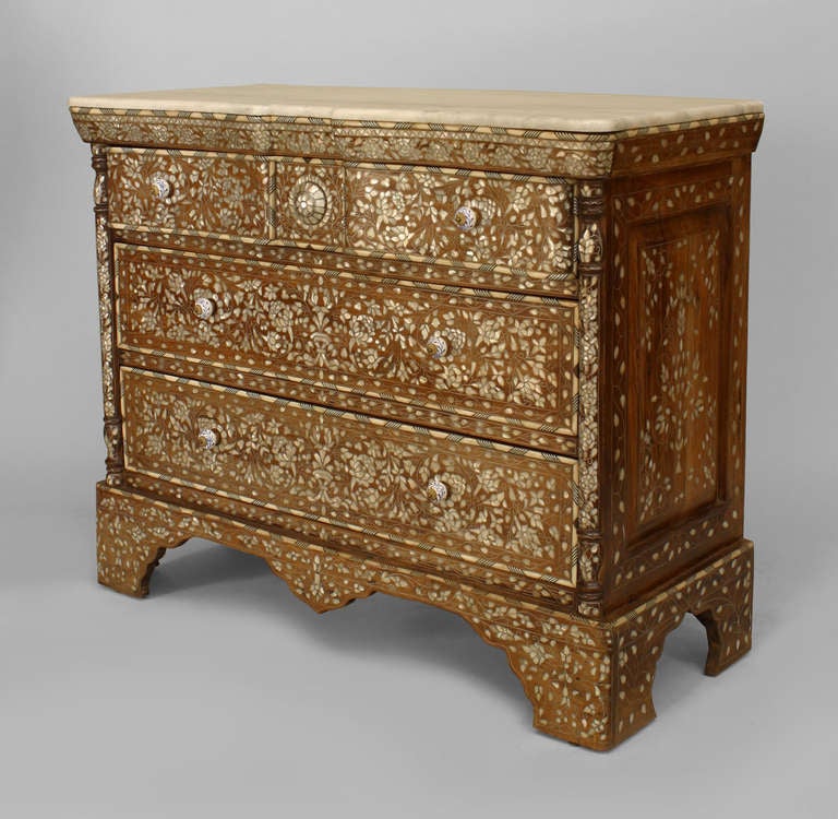 Middle Eastern chest of drawers detailed in floral mother of pearl inlay. The piece features a serpentine marble top, three drawers with porcelain pulls, and a platform base with Moorish-inspired cut outs.