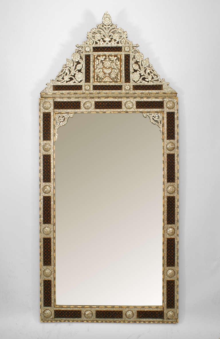 Large bevelled glass wall mirror composed of traditional Middle Eastern pearl, bone, and pewter inlay with decorative details such as a filigree pediment top and framed spindle and ball panels.