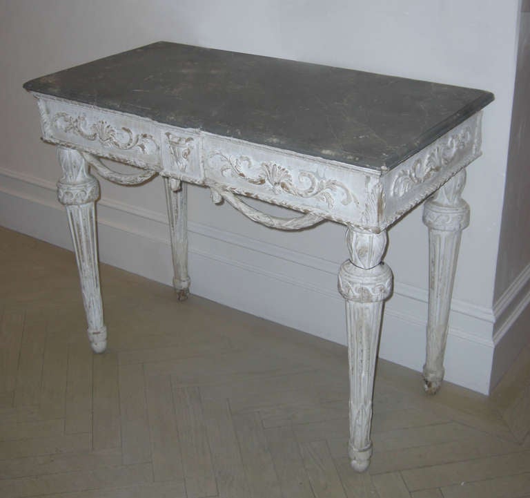 The faux marble top over a carved apron with swags supported by  round tapered fluted legs.