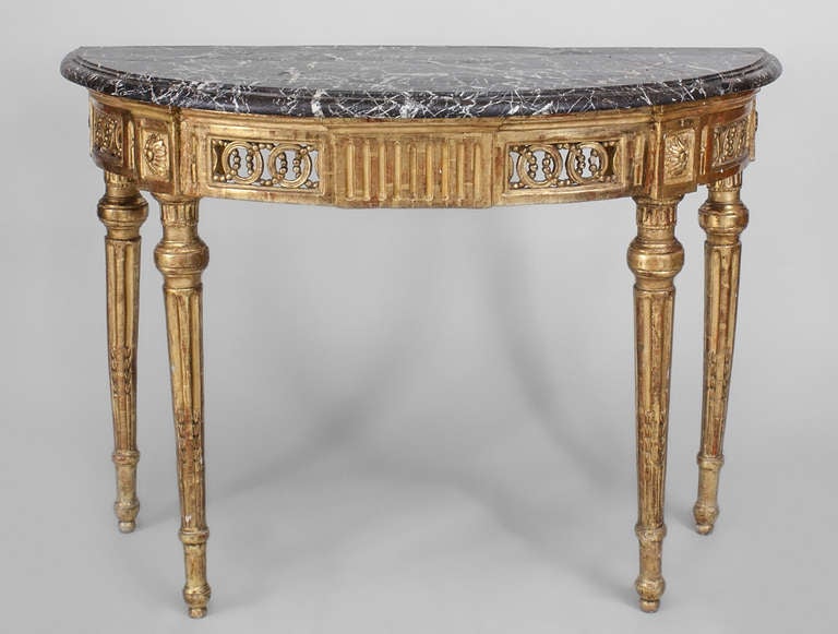 Neoclassic demi-lune console featuring a black marble top above an apron carved with interlocking circles, rosettes, and vertical glyphs supported by round fluted and tapered legs.
