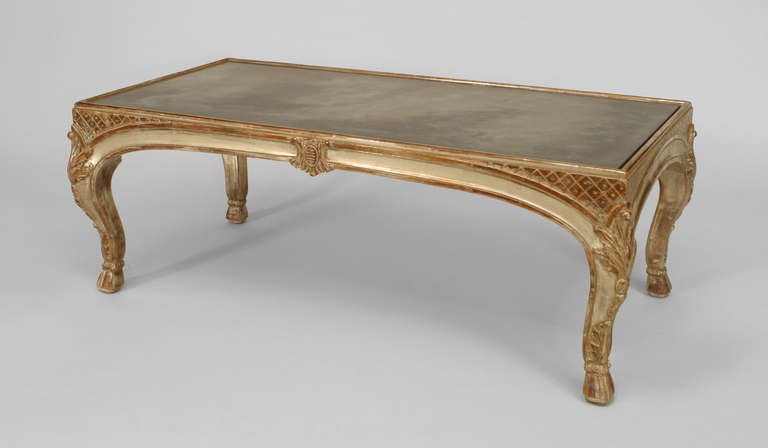 Bearing the stamp of French designer Jansen, this Louis VX style rectangular coffee table is composed of silver gilt and features decorative carvings as well as an inset smoked mirror top.