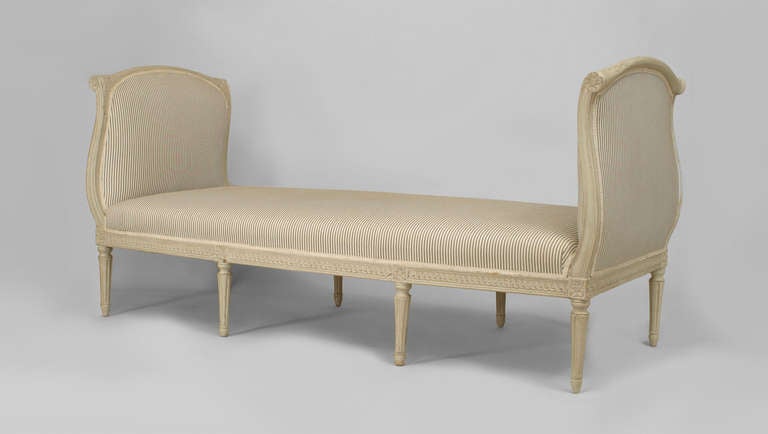Eighteenth century French white painted carved wood daybed supported by eight legs and upholstered in striped blue and white fabric.