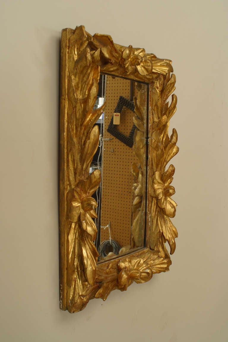 Rectangular Rococo wall mirror in a carved floral design gilt wood frame.