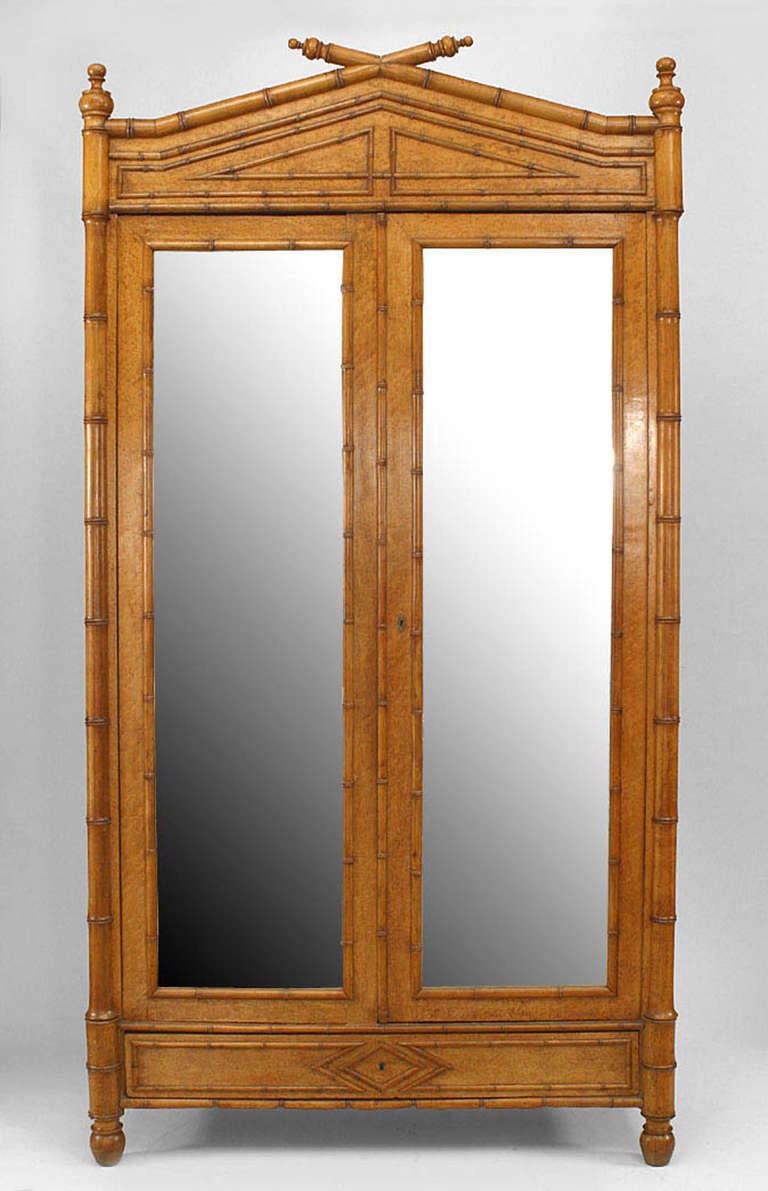 Nineteenth century French armoire cabinet composed of birds eye maple and featuring two mirrored glass doors, a bottom drawer, and a pediment and trim with faux bamboo accents.