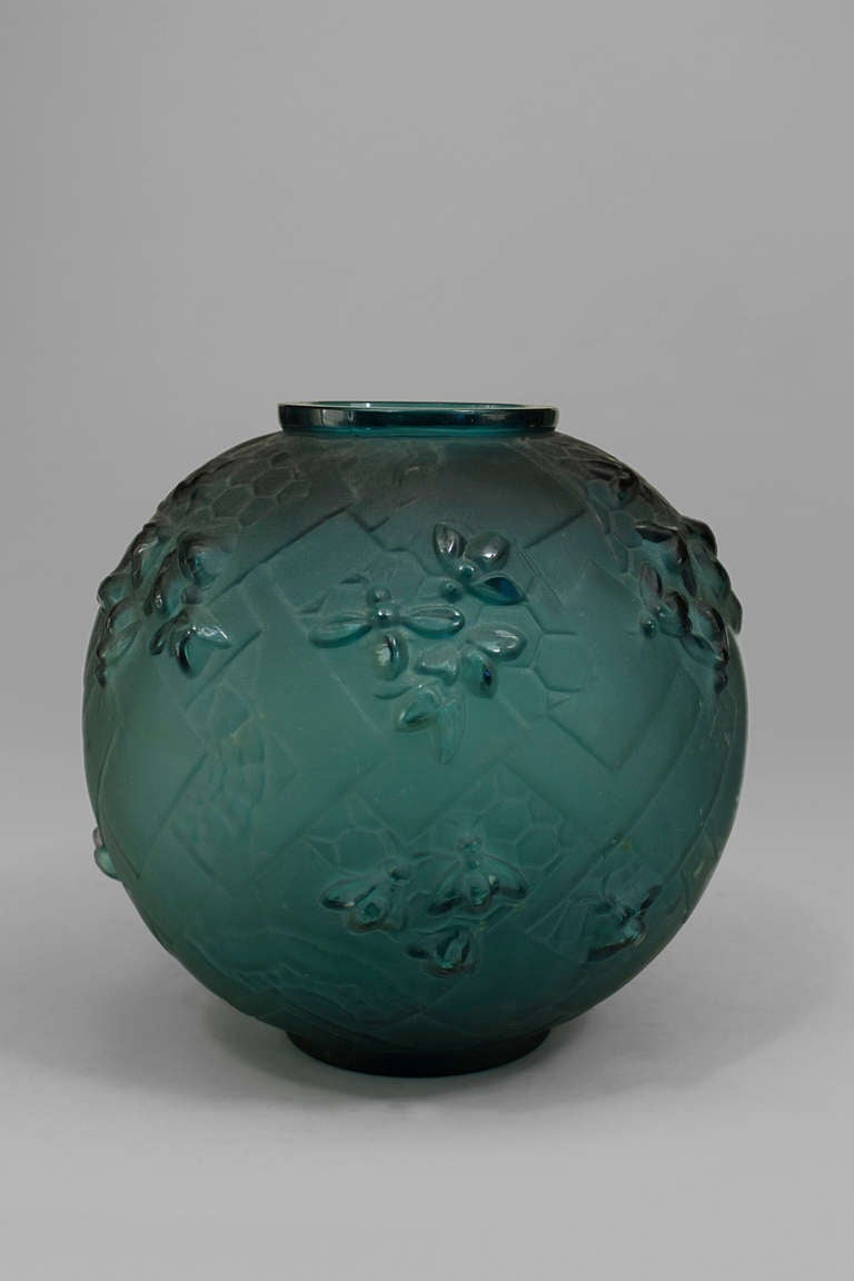 Signed by French designer Sabino, this ball-shaped Art Deco vase is composed of green glass molded with geometric bee and honeycomb reliefs.
